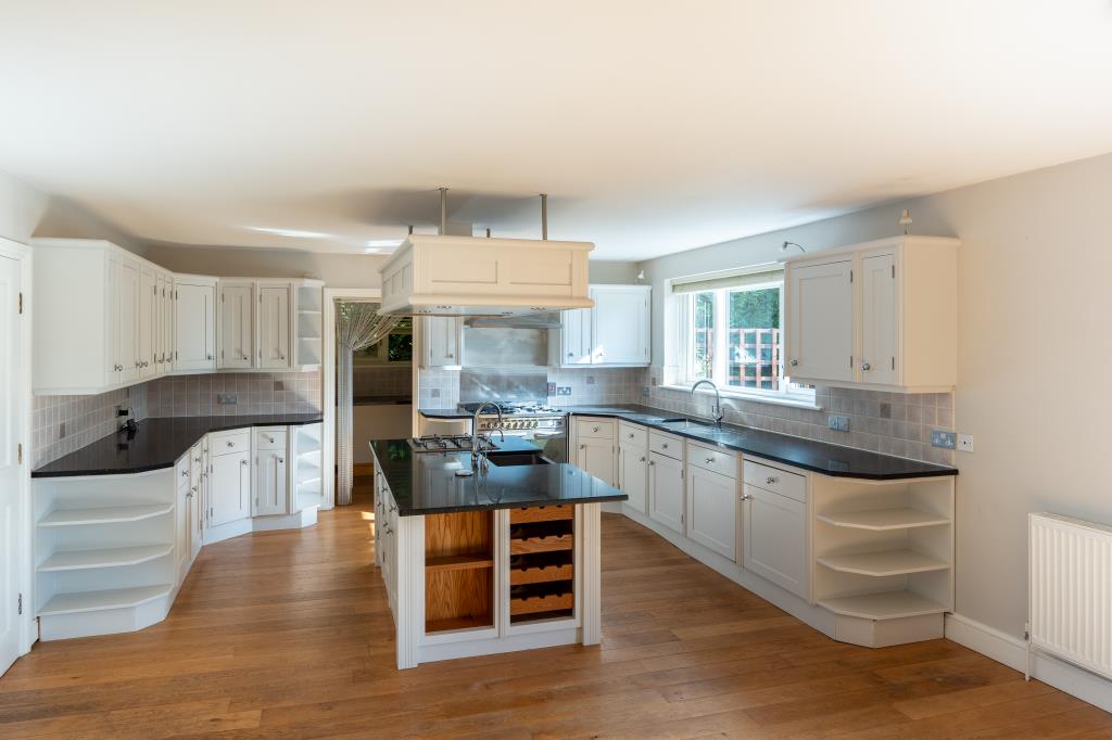 Lot: 164 - THREE-BEDROOM HOUSE IN SECLUDED LOCATION OVERLOOKING WOODLAND - Modern kitchen with island and wood effect floor